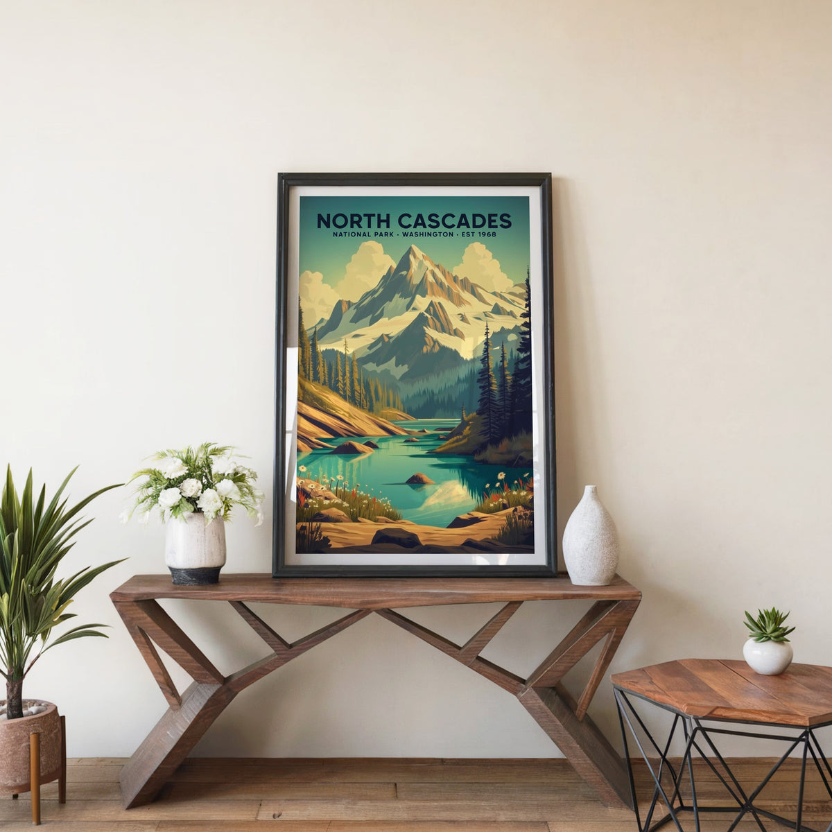 North Cascades poster in a black frame on an entryway console table beside white flowers and a yucca