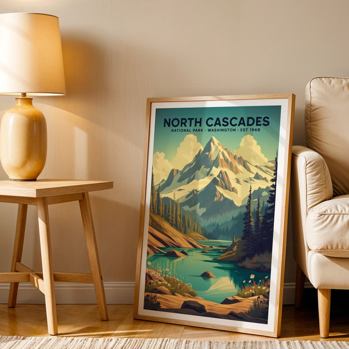 North Cascades print in an oak frame beside a cream armchair and an amber lamp in warm afternoon light