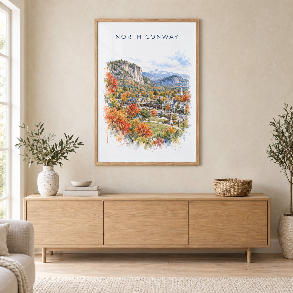 North Conway, New Hampshire watercolor print in an oak frame above a light wood sideboard in a Scandinavian living room