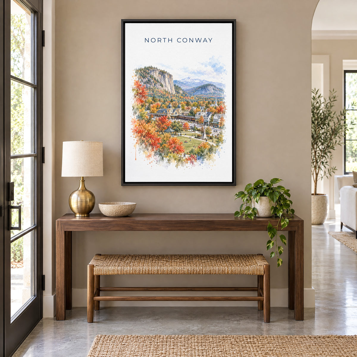 North Conway, New Hampshire watercolor print as a black floater canvas above a walnut console and woven bench in an entryway