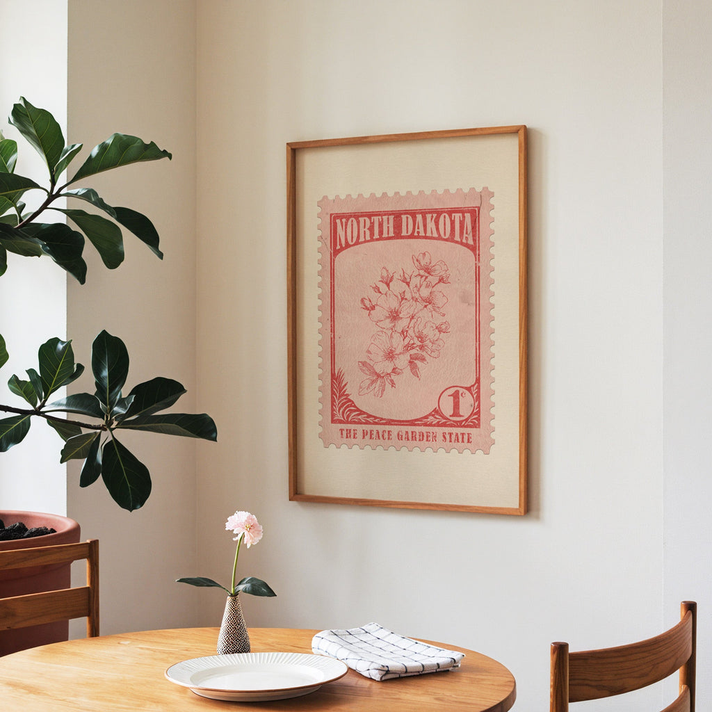 North Dakota state flower print framed above a round wooden table with a single bloom in a vase and books