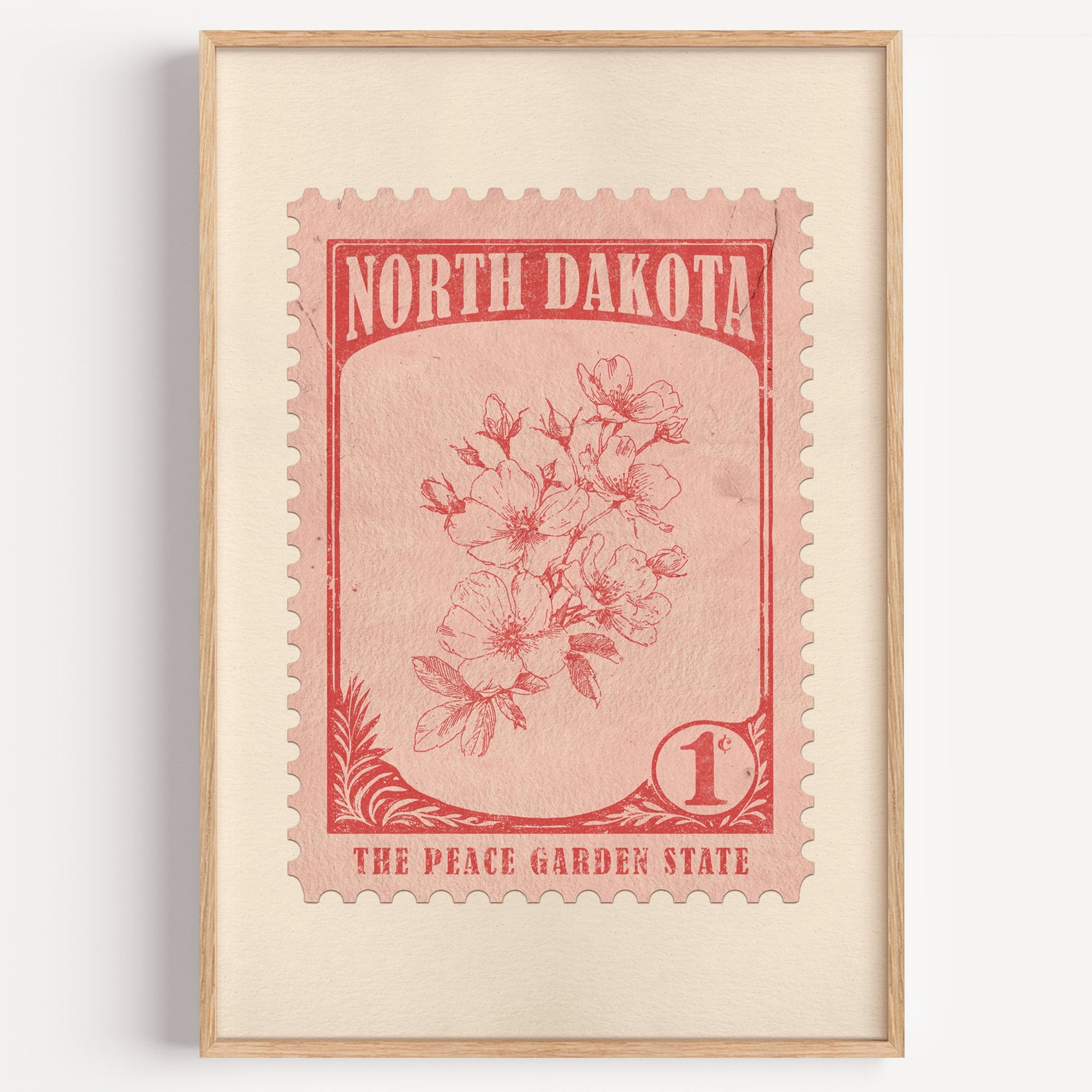 North Dakota state flower stamp print in brick red on blush, light oak frame on a plain white wall