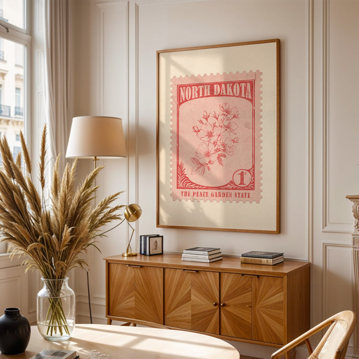 North Dakota stamp print framed above a wooden sideboard, pampas grass in a glass vase and a floor lamp