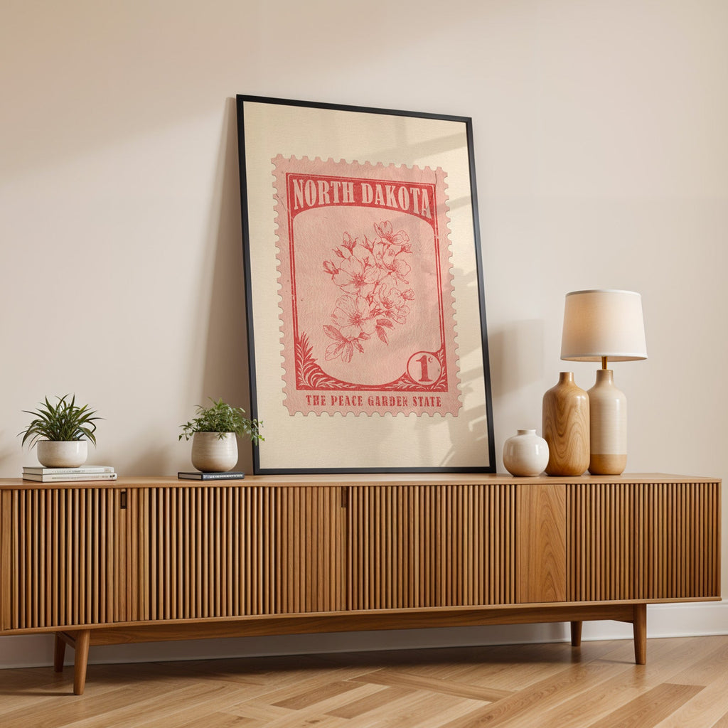 North Dakota state flower print in a black frame leaning on a fluted wood credenza with vases and a lamp
