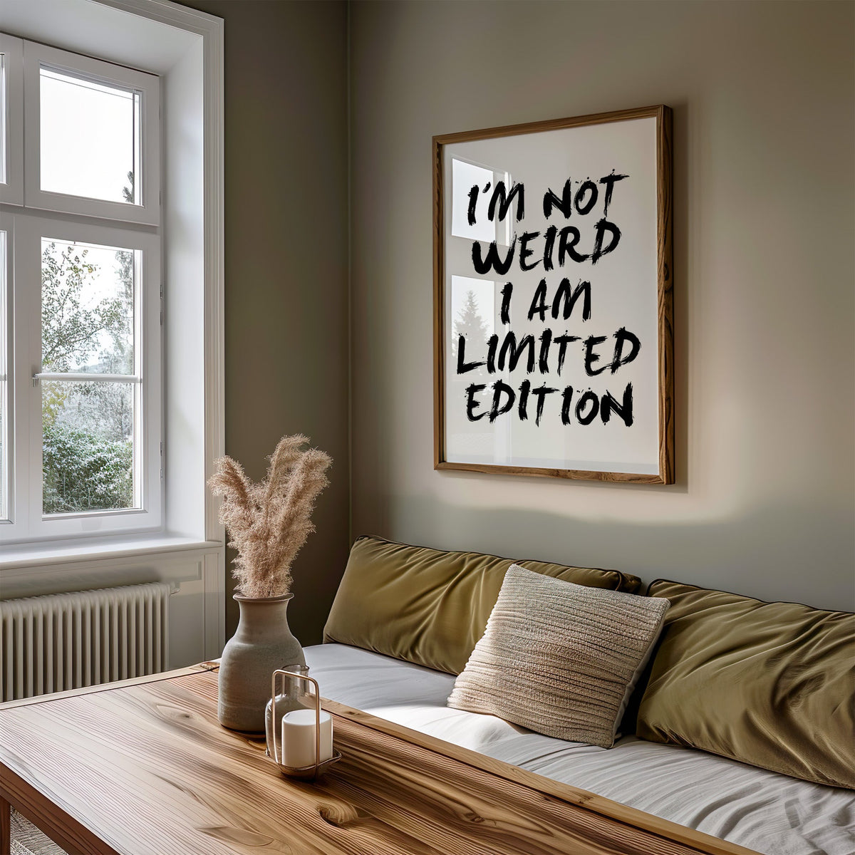 I'm not weird brush lettering quote print in a walnut frame above an olive daybed by a window