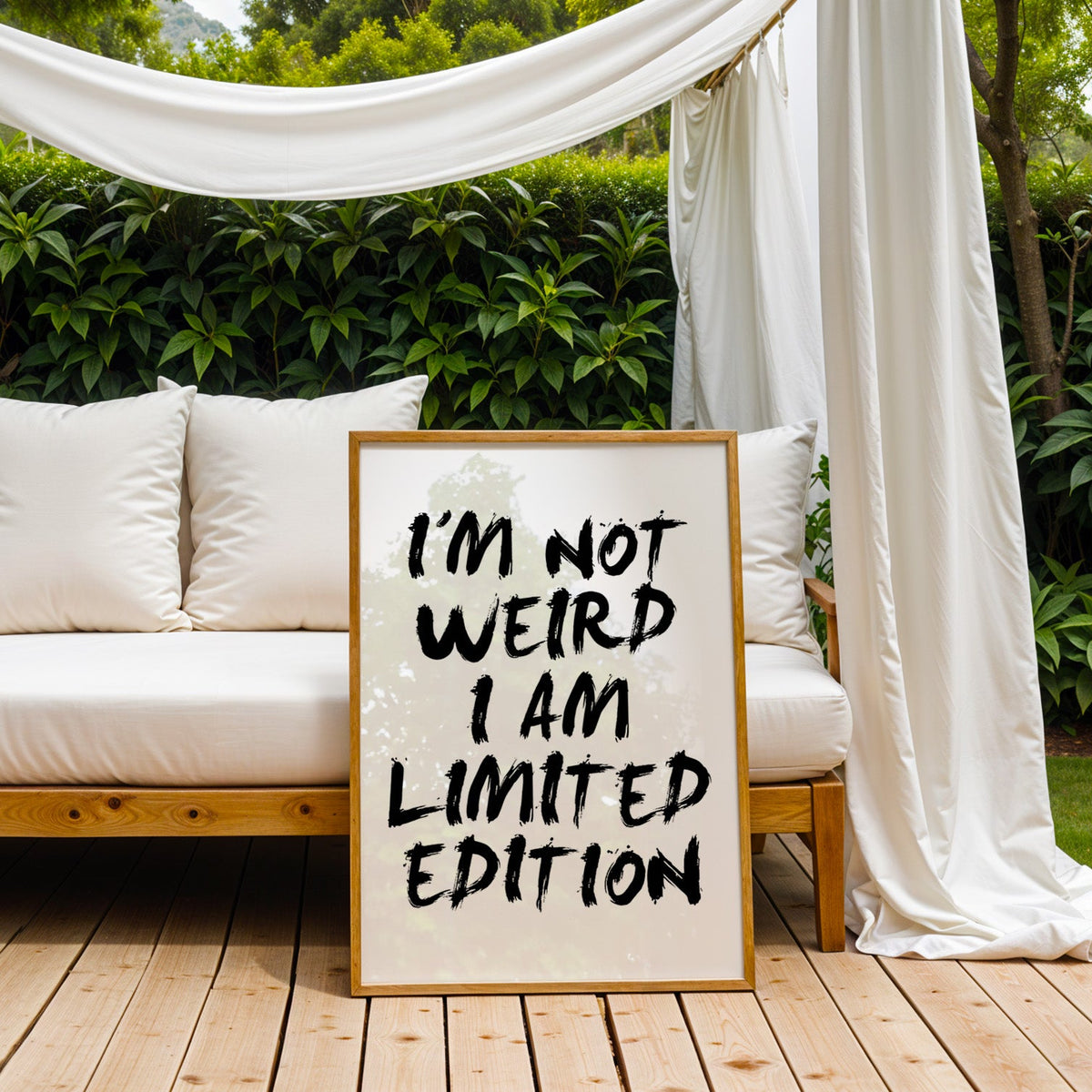 I'm not weird brush lettering quote print in an oak frame on an outdoor daybed under white drapes