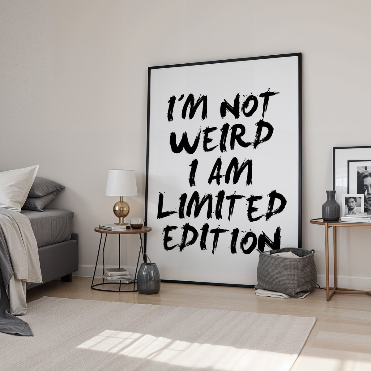 I'm not weird brush lettering quote print in a black frame leaning in a bedroom beside a gold lamp