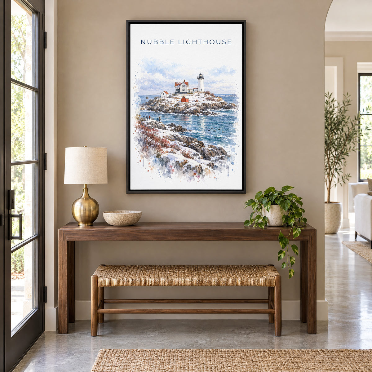 Nubble Lighthouse watercolor print as a black floater canvas above a walnut console and woven bench in an entryway
