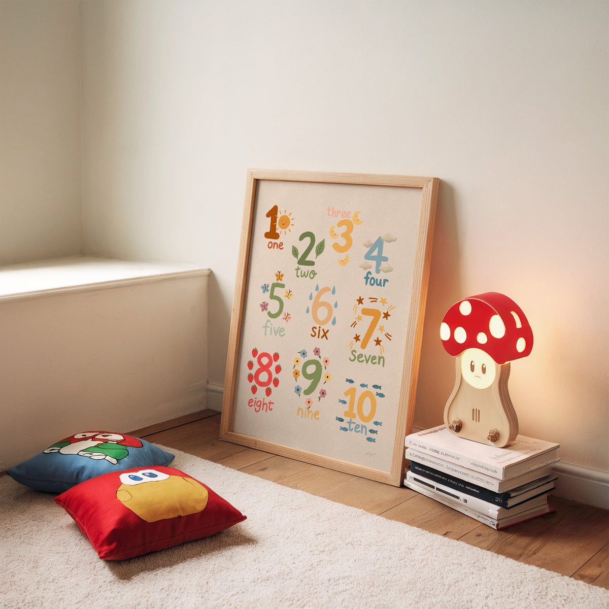 Numbers one to ten counting chart nursery print in an oak frame leaning on a rug beside a mushroom lamp and floor cushions