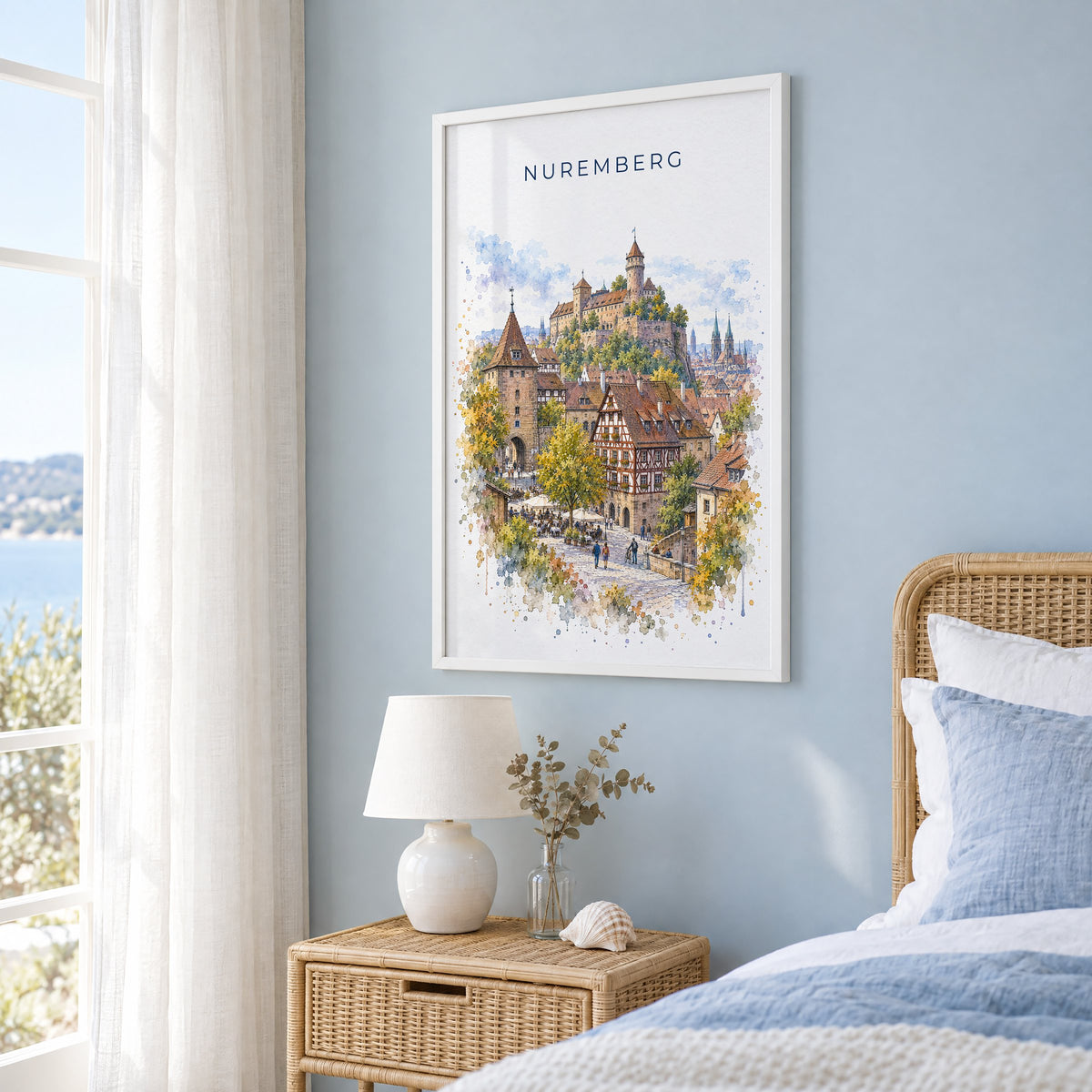Nuremberg watercolor print in a white frame on a pale blue wall beside a rattan bed in a coastal bedroom