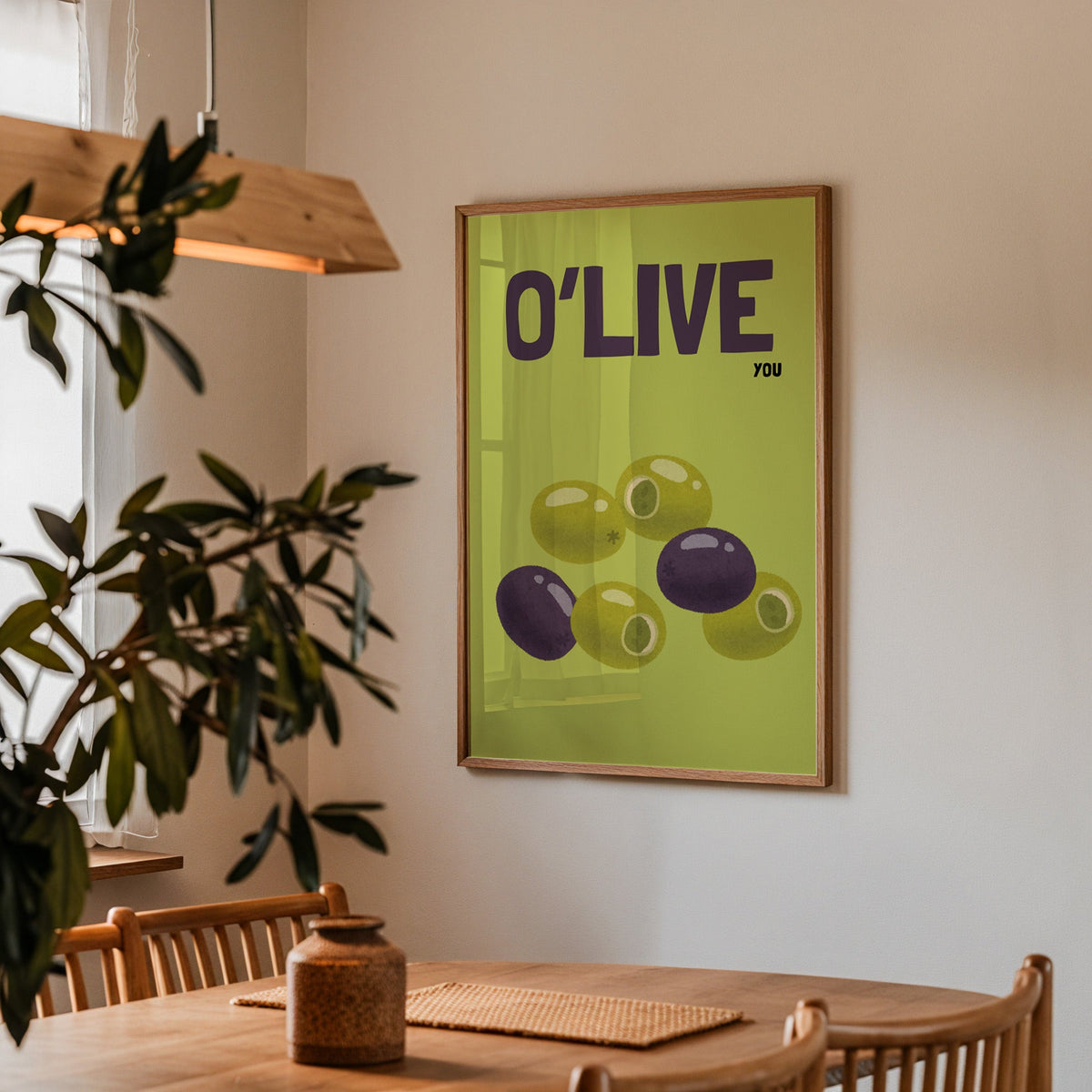 O Live You olives print in a walnut frame above a dining table with olive branches