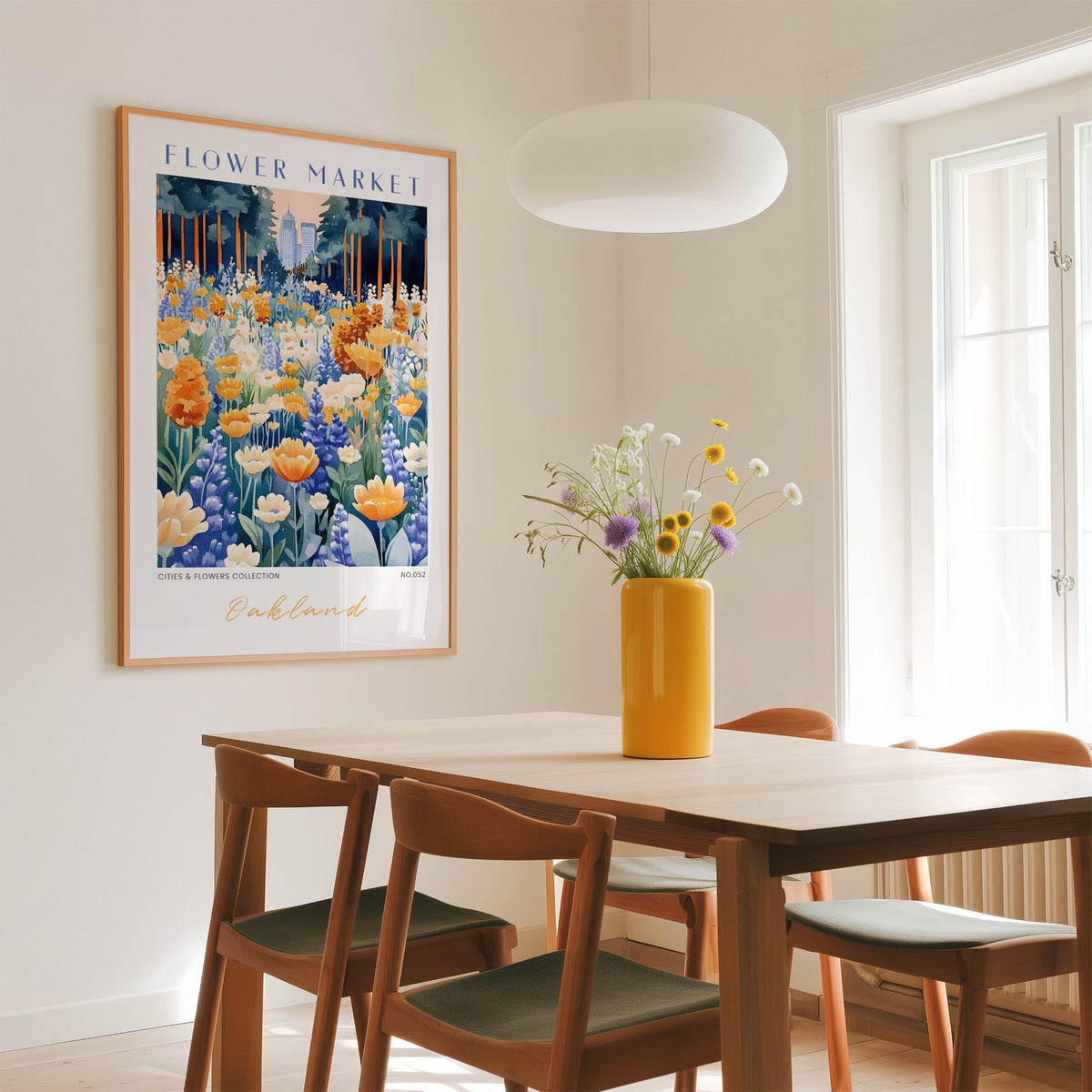 Oakland flower market print in an oak frame above a dining table with a yellow vase and white pendant light