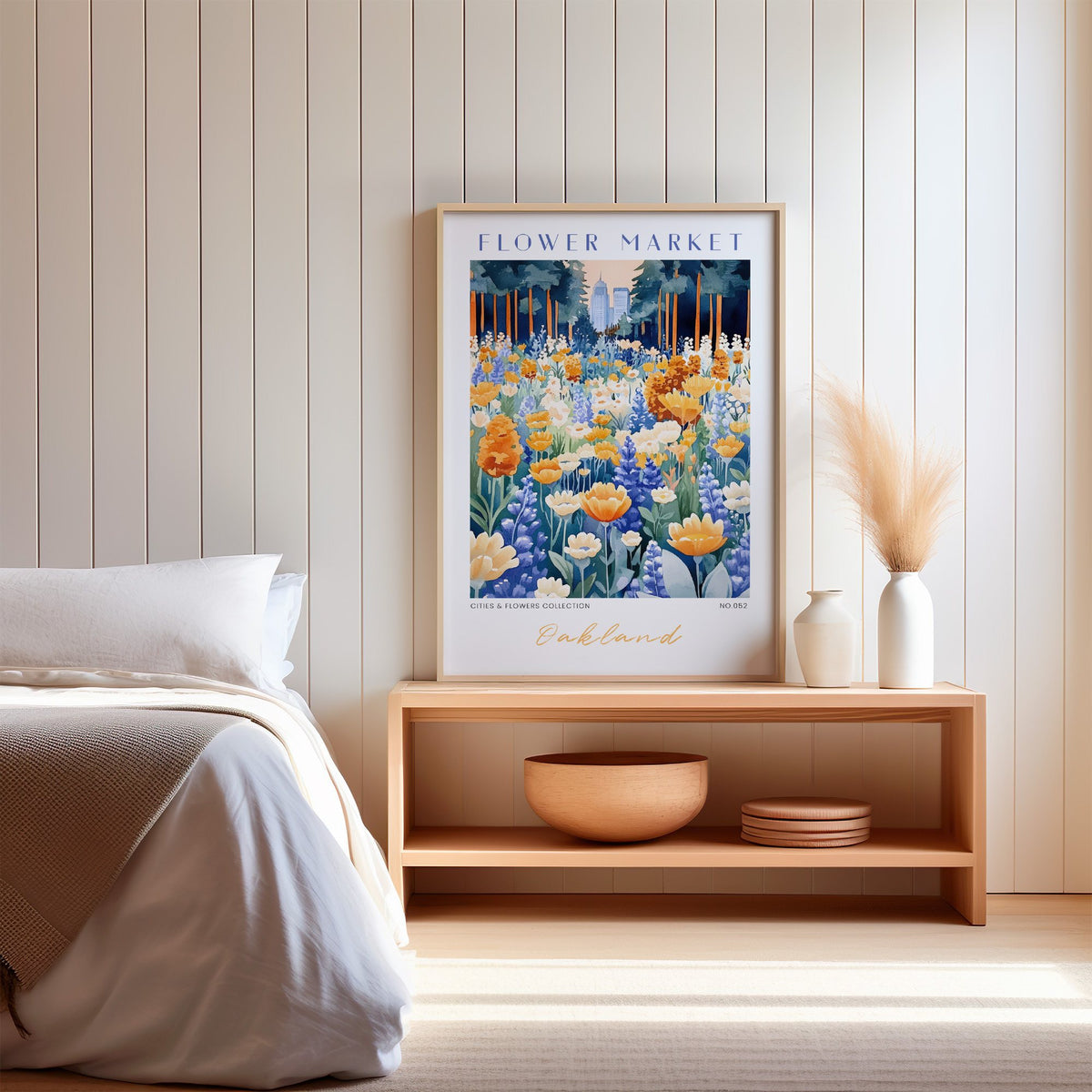 Oakland flower market print in an oak frame on a wood bench against a white shiplap bedroom wall with pampas grass