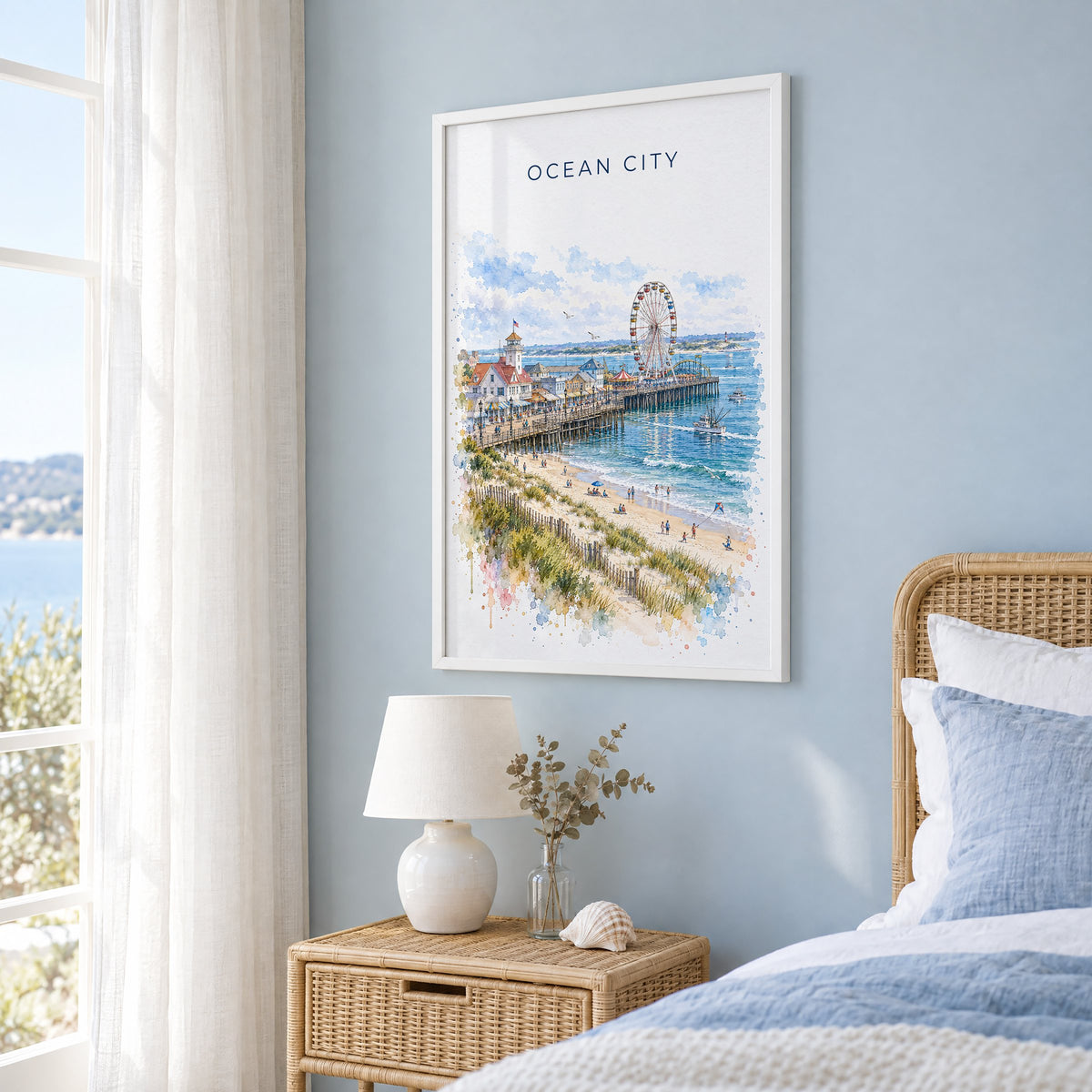 Ocean City, Maryland watercolor print in a white frame on a pale blue wall beside a rattan bed in a coastal bedroom