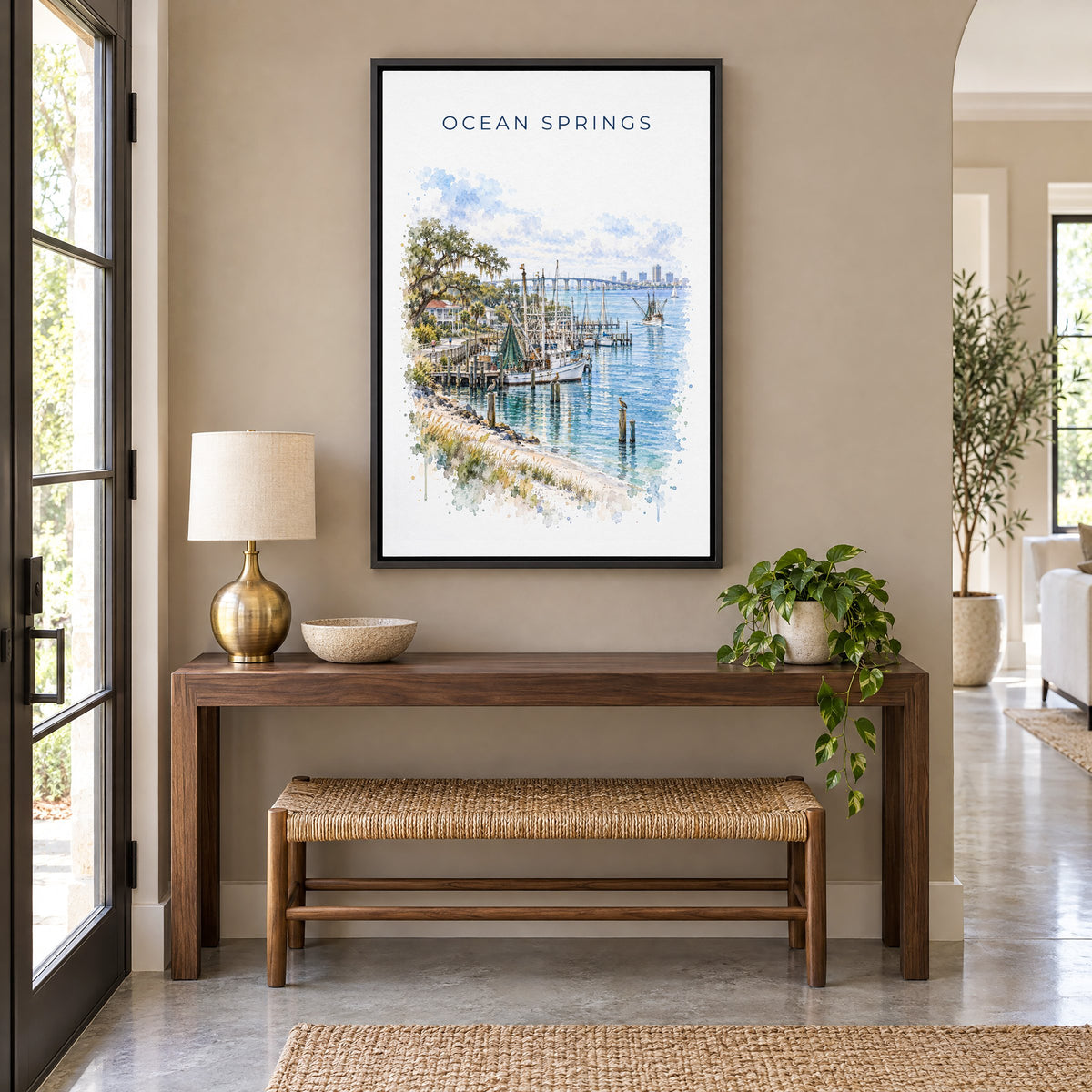 Ocean Springs, Mississippi watercolor print as a black floater canvas above a walnut console and woven bench in an entryway