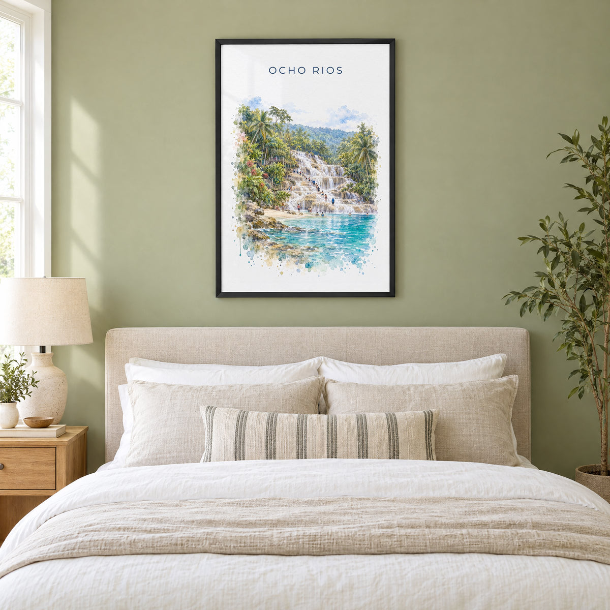 Ocho Rios watercolor print in a black frame above an upholstered headboard in a sage green bedroom
