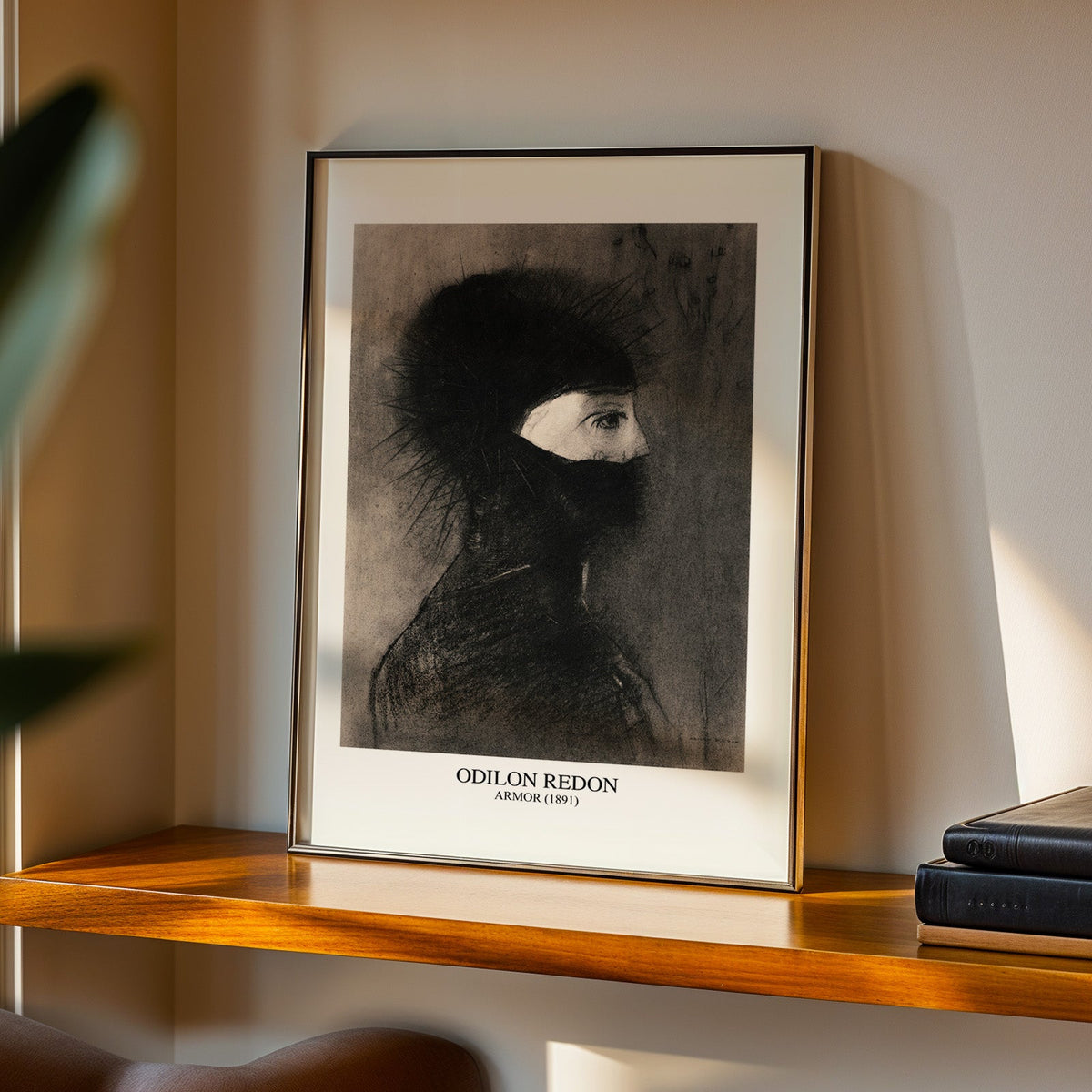 Redon noir print in a black frame on a walnut shelf in evening light