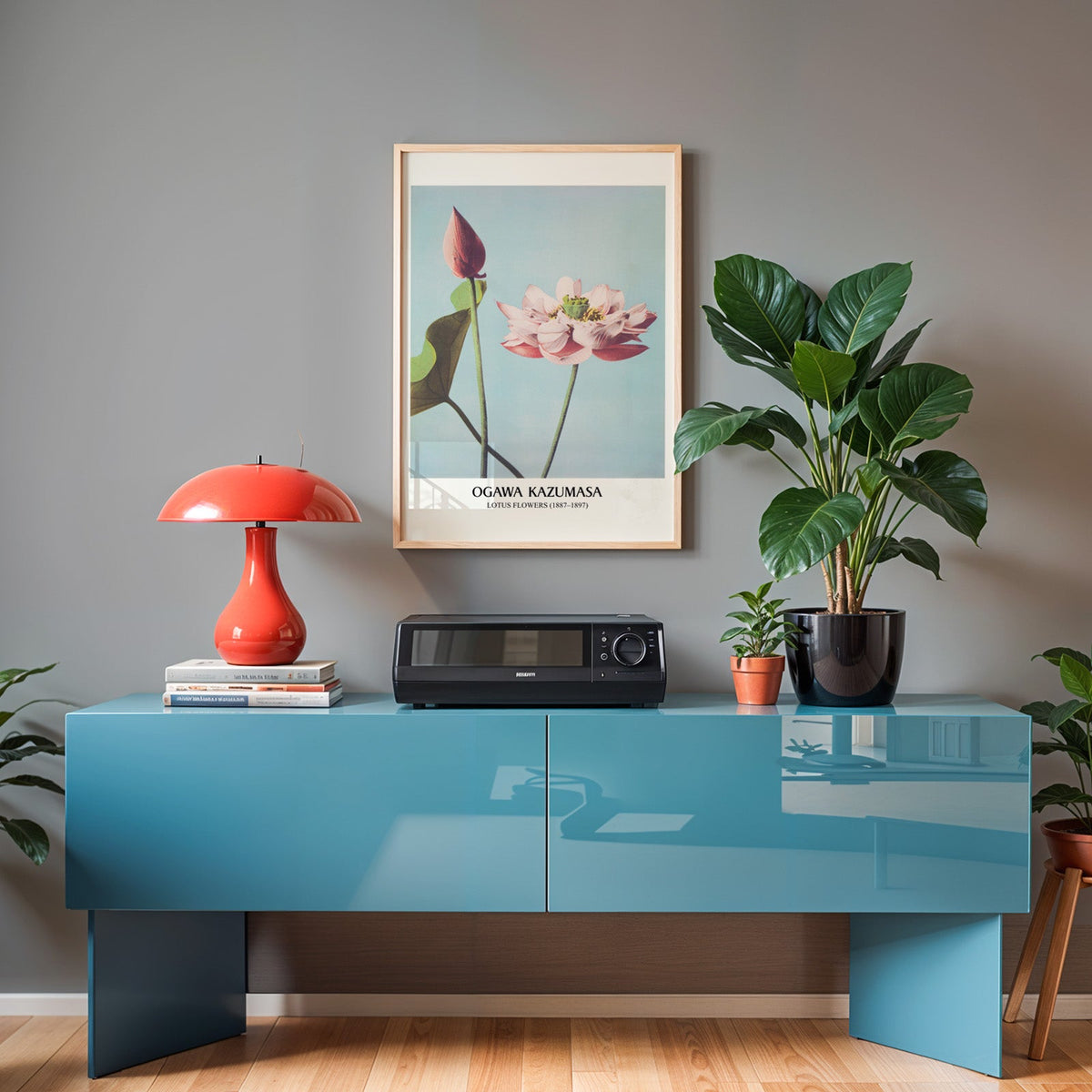 Pink lotus print in an oak frame above a teal sideboard with a red lamp