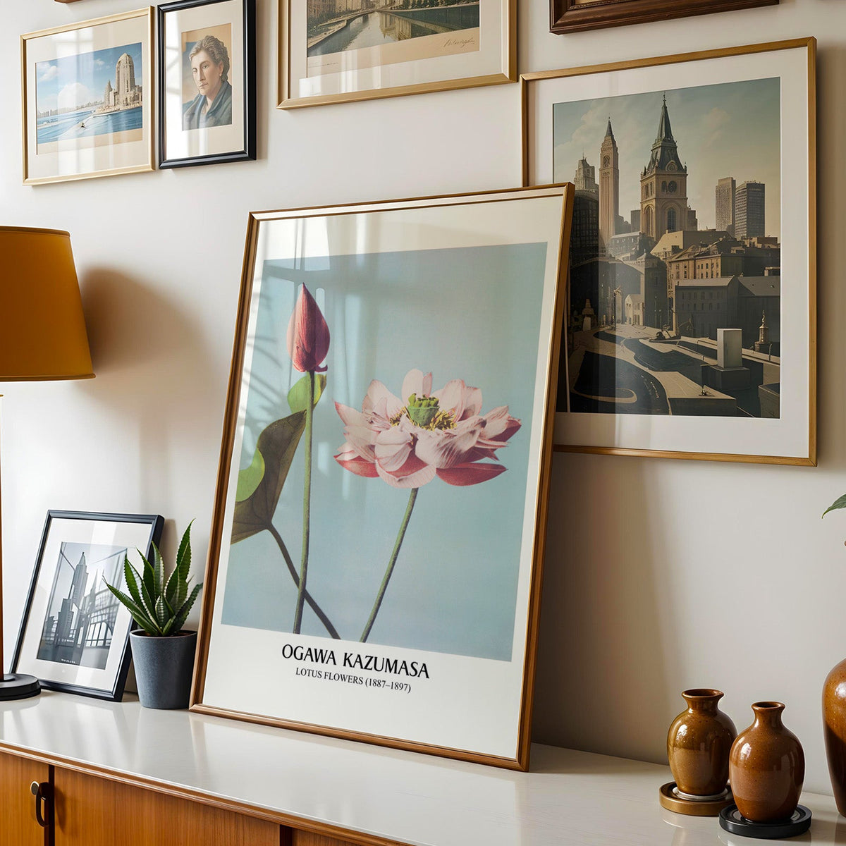 Lotus print shown in a gold frame leaning on a sideboard in a gallery wall