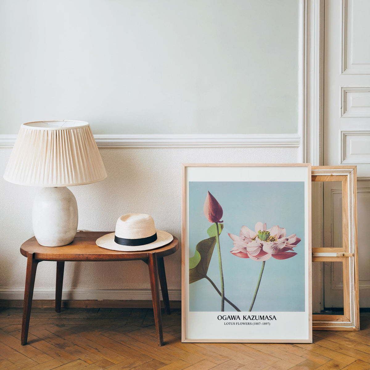 Japanese botanical poster in a light wood frame leaning by a bench and hat