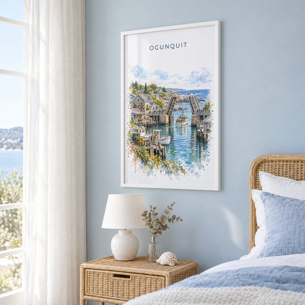 Ogunquit watercolor print in a white frame on a pale blue wall beside a rattan bed in a coastal bedroom