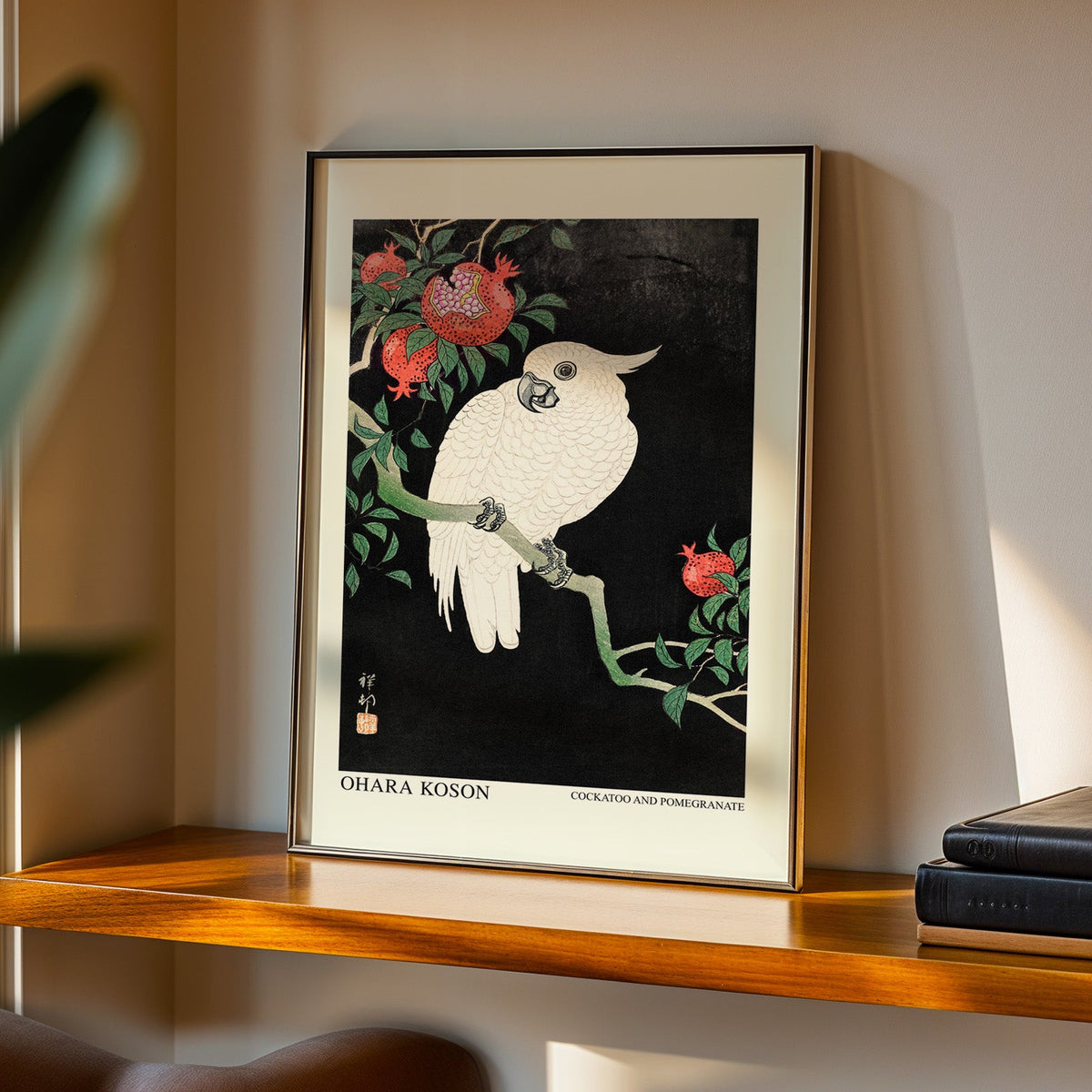 Cockatoo and Pomegranate print in a black frame on a walnut shelf