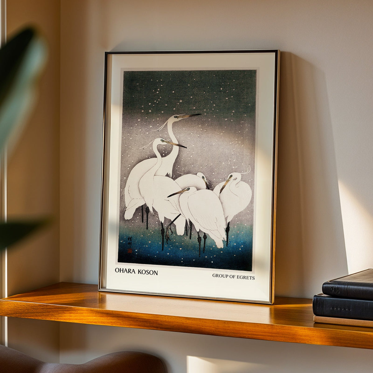 Group of Egrets print in a black frame on a walnut shelf in evening light