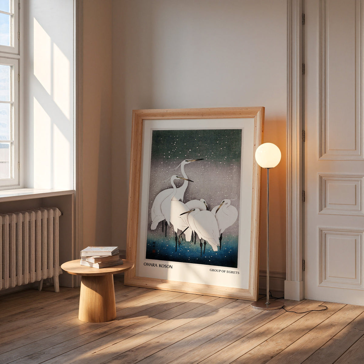Koson egret print in a wide pine frame leaning by a sunlit window