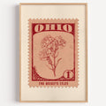 Ohio state flower stamp print in dark red on peach, light oak frame on a plain white wall