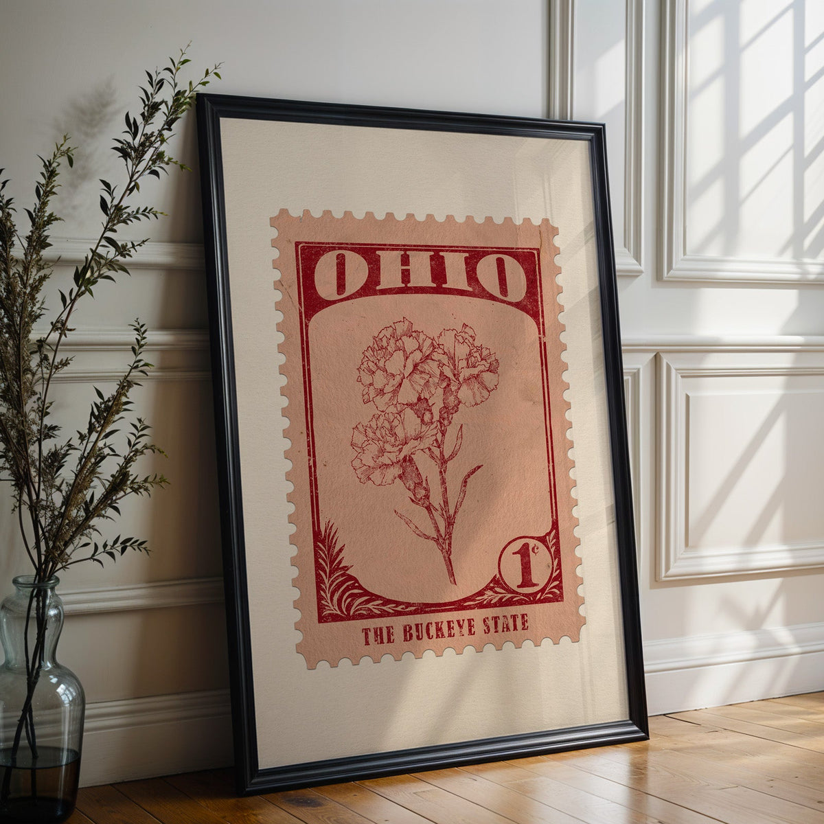 Ohio state flower print in a black frame leaning against a white panelled wall beside olive branches