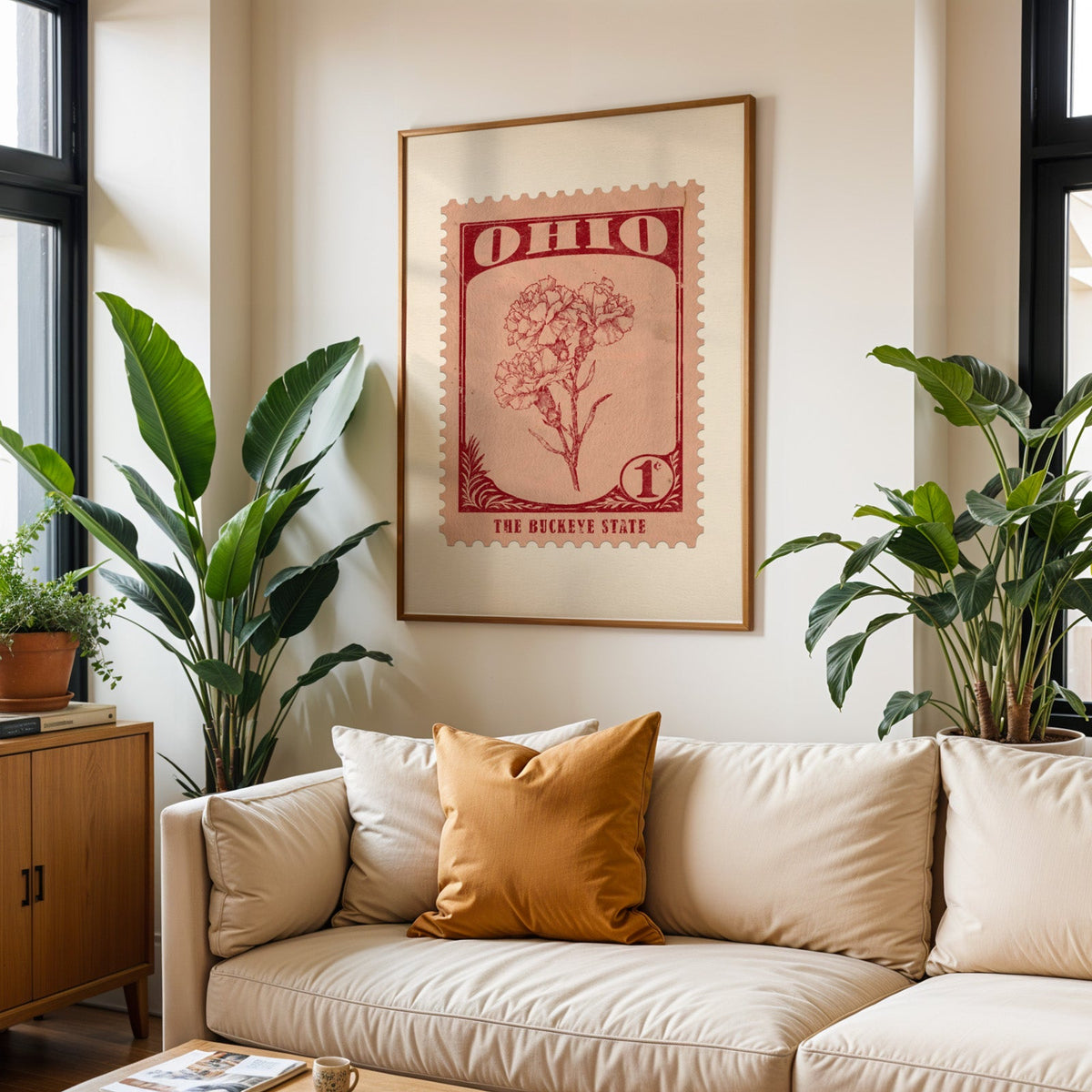 Ohio state flower print framed above a cream sofa with an ochre cushion and large plants either side
