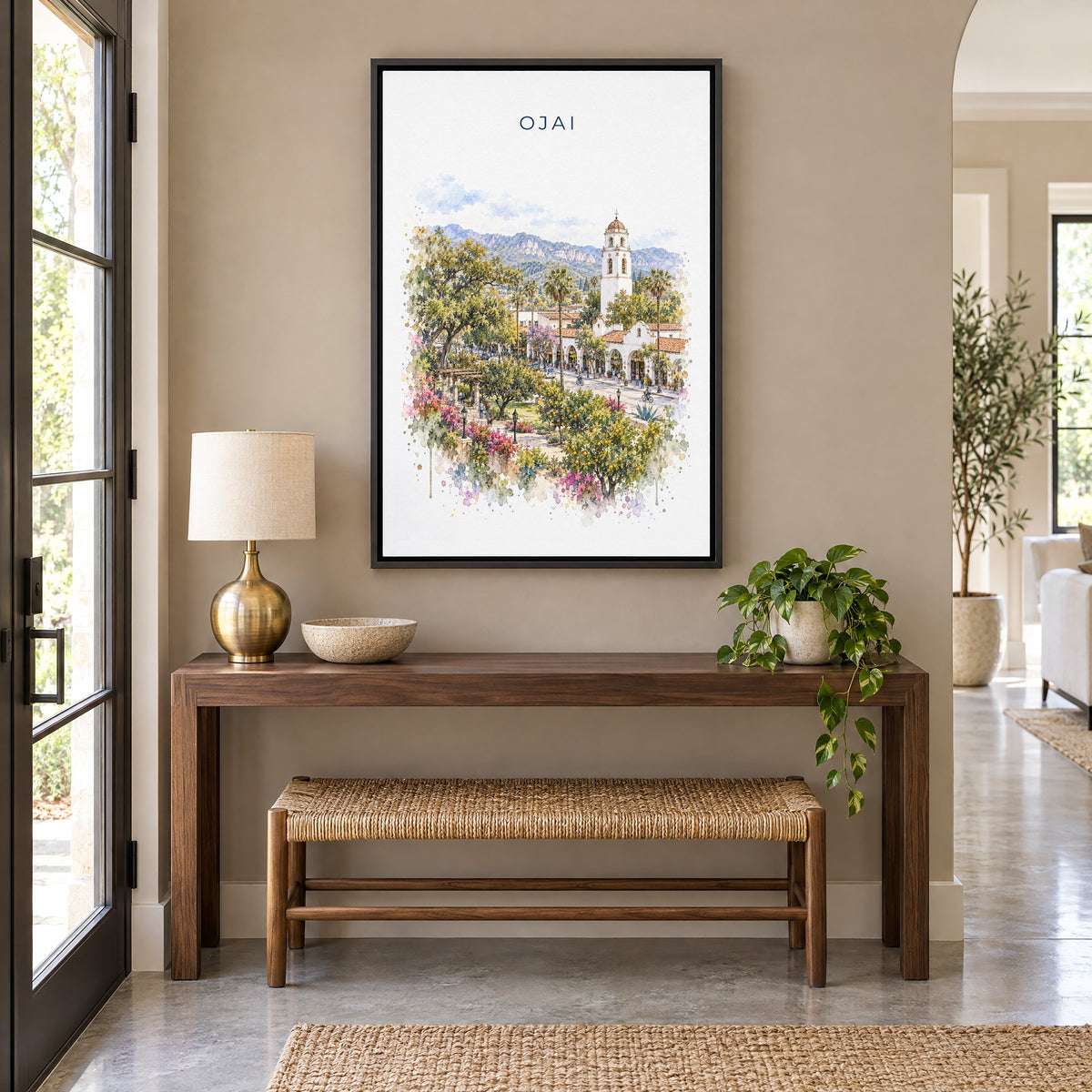 Ojai, California watercolor print as a black floater canvas above a walnut console and woven bench in an entryway