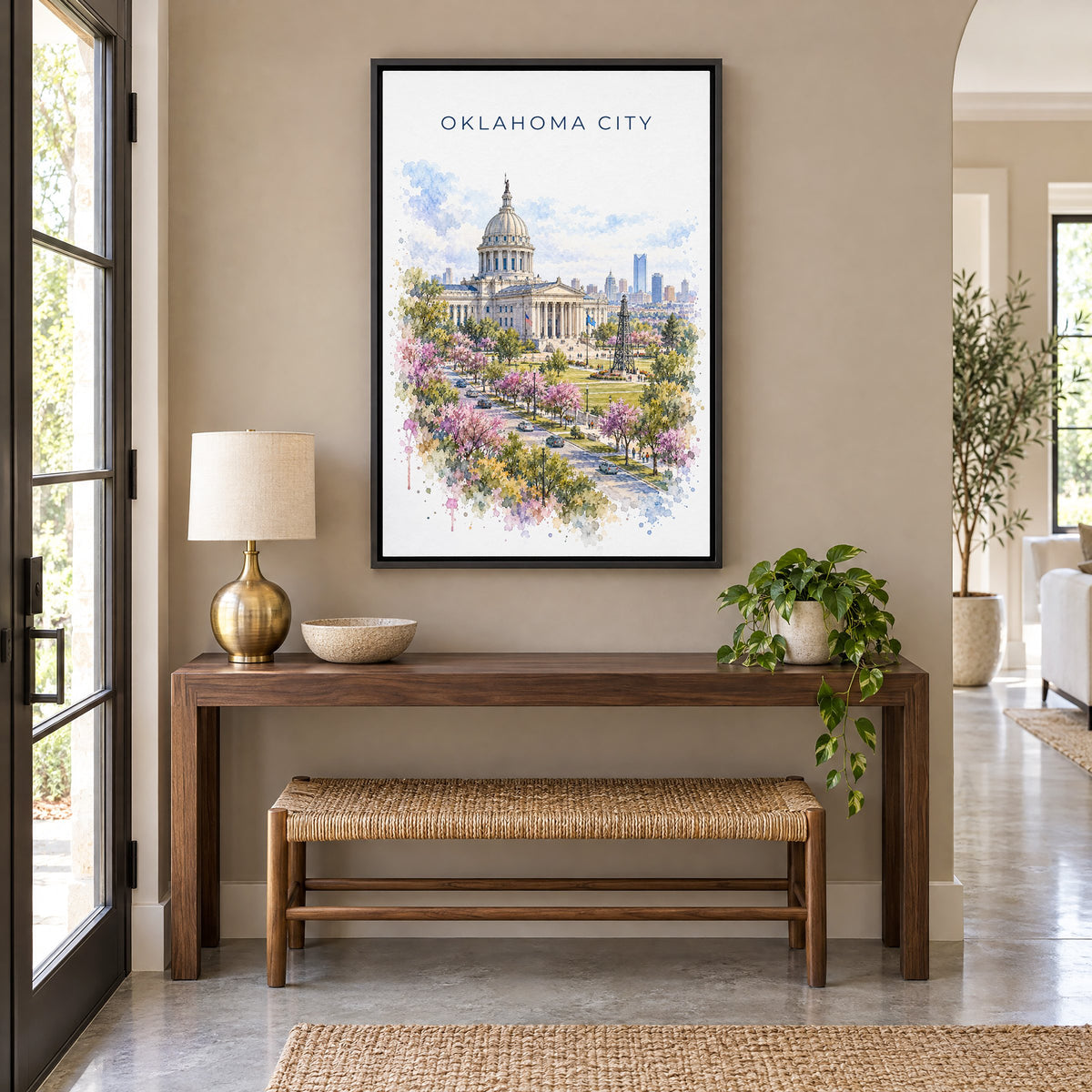 Oklahoma City watercolor print as a black floater canvas above a walnut console and woven bench in an entryway
