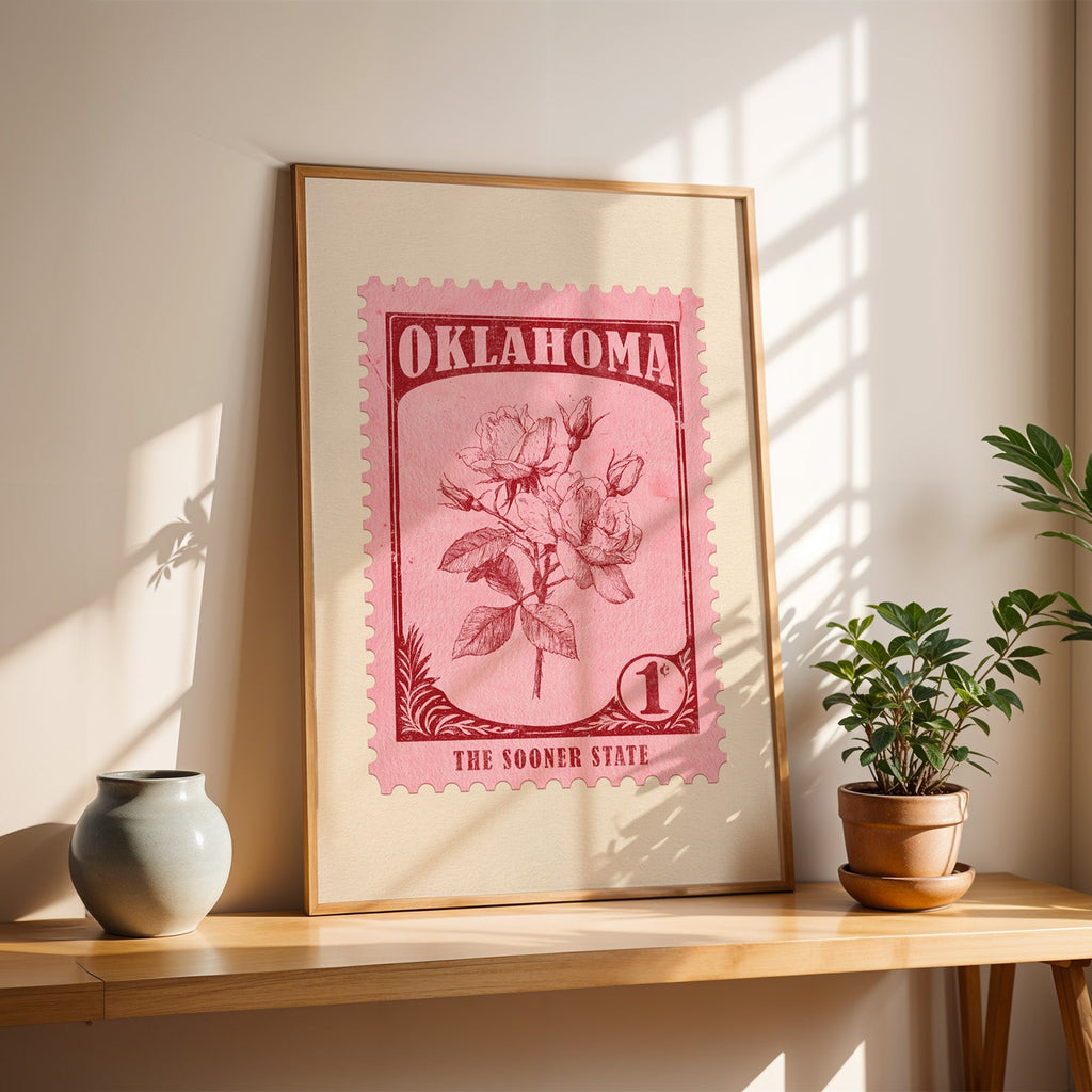 Oklahoma Rose stamp print in a light oak frame leaning on a wooden table beside a stoneware vase