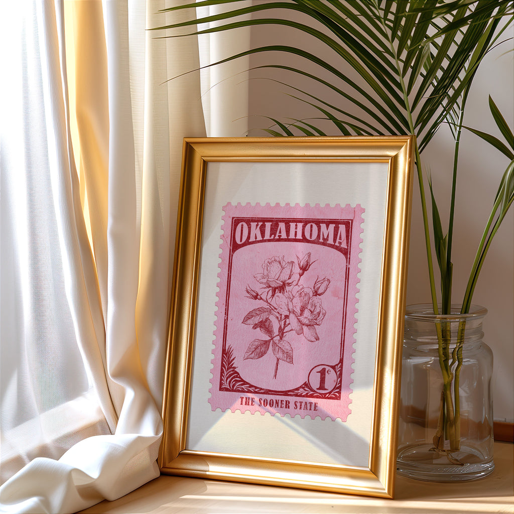 Oklahoma stamp print in a gold frame leaning by a cream curtain with a palm in a glass jar