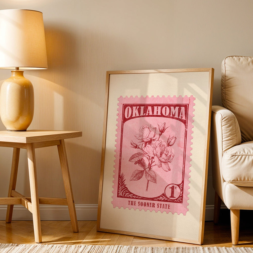 Oklahoma stamp print in a wood frame resting on the floor beside a beige armchair and a yellow lamp