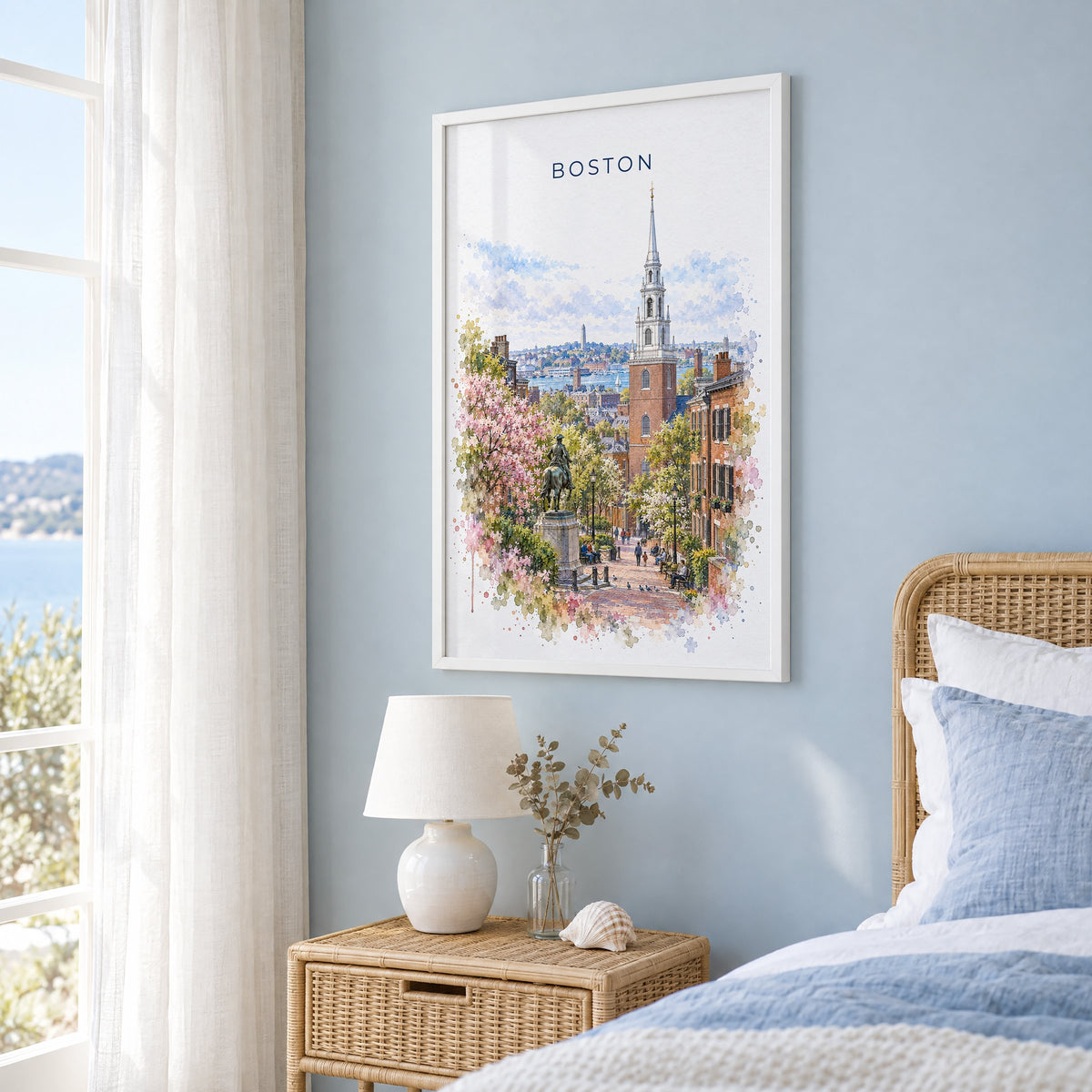 Old North Church Boston watercolor print in a white frame on a pale blue wall beside a rattan bed in a coastal bedroom
