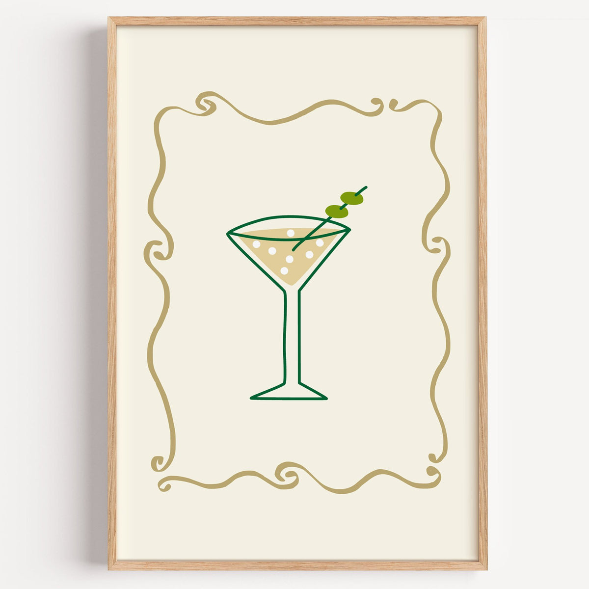 Olive martini in gold scroll frame print in a light oak frame on a plain white wall