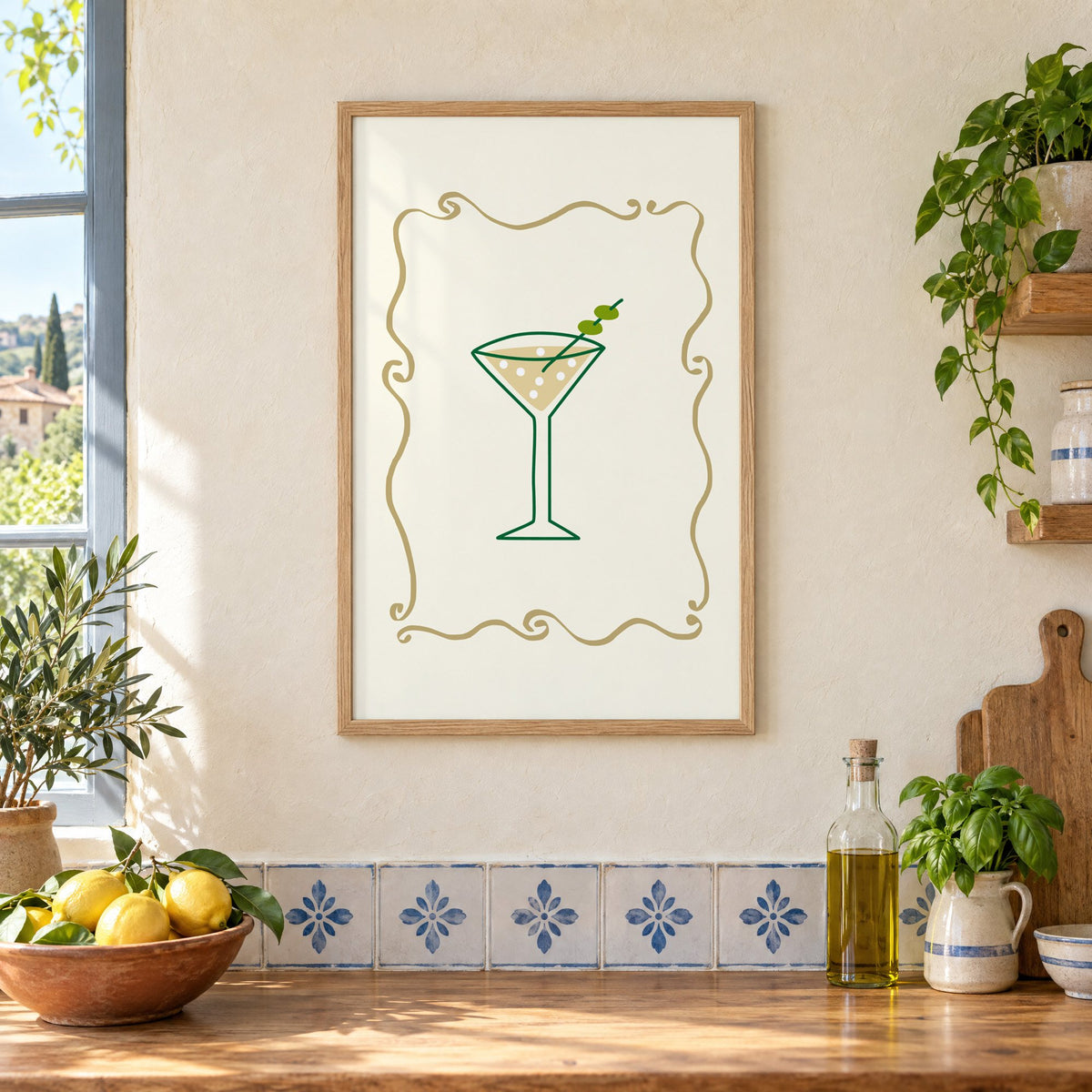 Olive martini in gold scroll frame print in an oak frame on a cream plaster wall above a worktop with a bowl of lemons and blue-and-white tiles