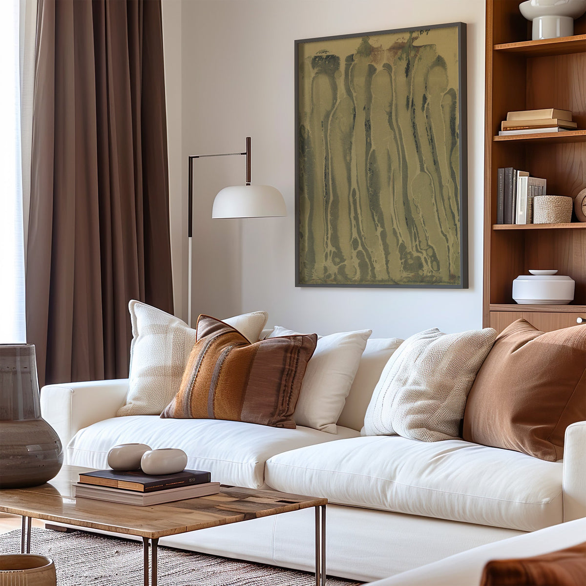 Olive and sepia marbled ink drips print in a black frame above a cream sofa with brown striped pillows