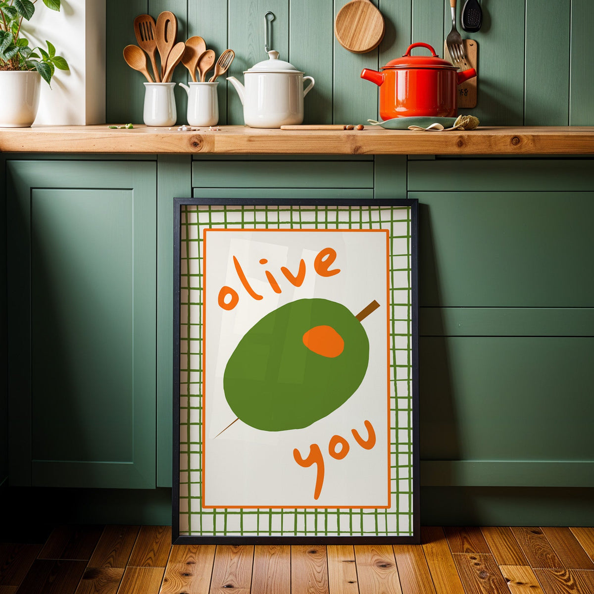 Olive you green olive print in a black frame against sage green kitchen cabinets
