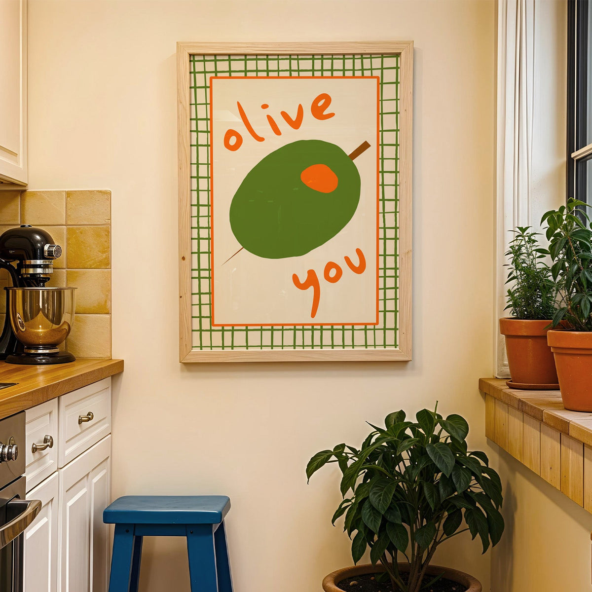 Olive you green olive print in a wood frame on a yellow tiled kitchen wall
