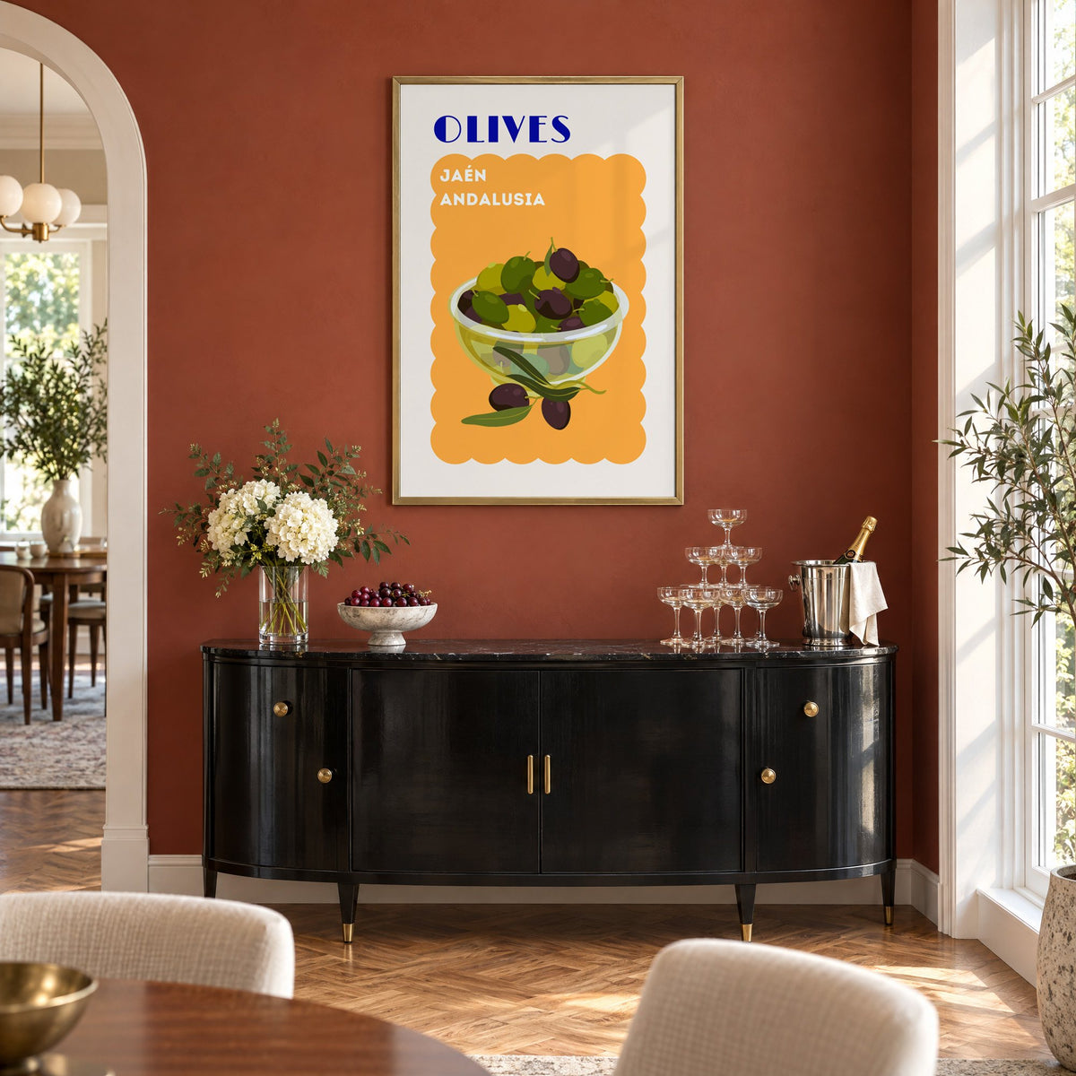 OLIVES Jaén Andalusia orange print in a brass frame on a terracotta wall above a black buffet with a champagne tower