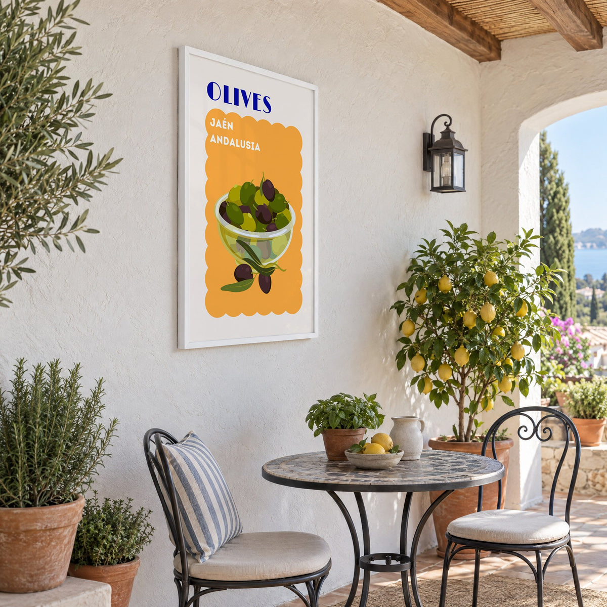 OLIVES Jaén Andalusia orange print in a white frame on a sunny patio wall beside a potted lemon tree