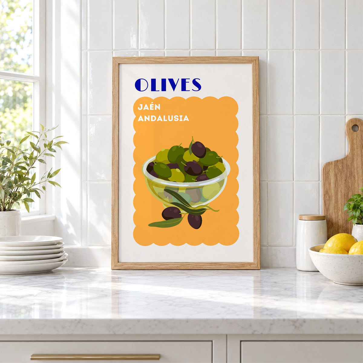 OLIVES Jaén Andalusia orange print in an oak frame leaning on a marble counter by white tiles and lemons