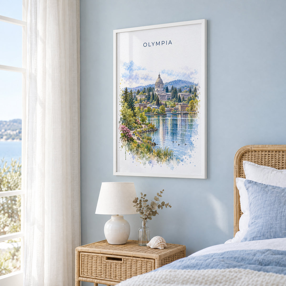Olympia, Washington watercolor print in a white frame on a pale blue wall beside a rattan bed in a coastal bedroom