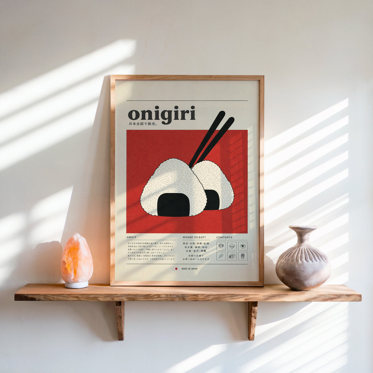 onigiri rice balls on red print in an oak frame on a live-edge wall shelf with a salt lamp and clay vase
