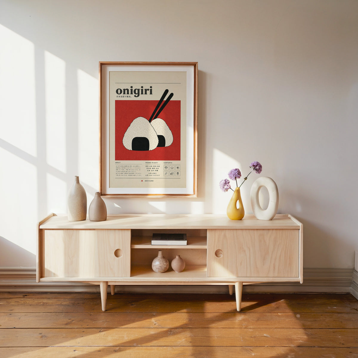 onigiri rice balls on red print shown in a wood frame with a white mat above a pale wood media console