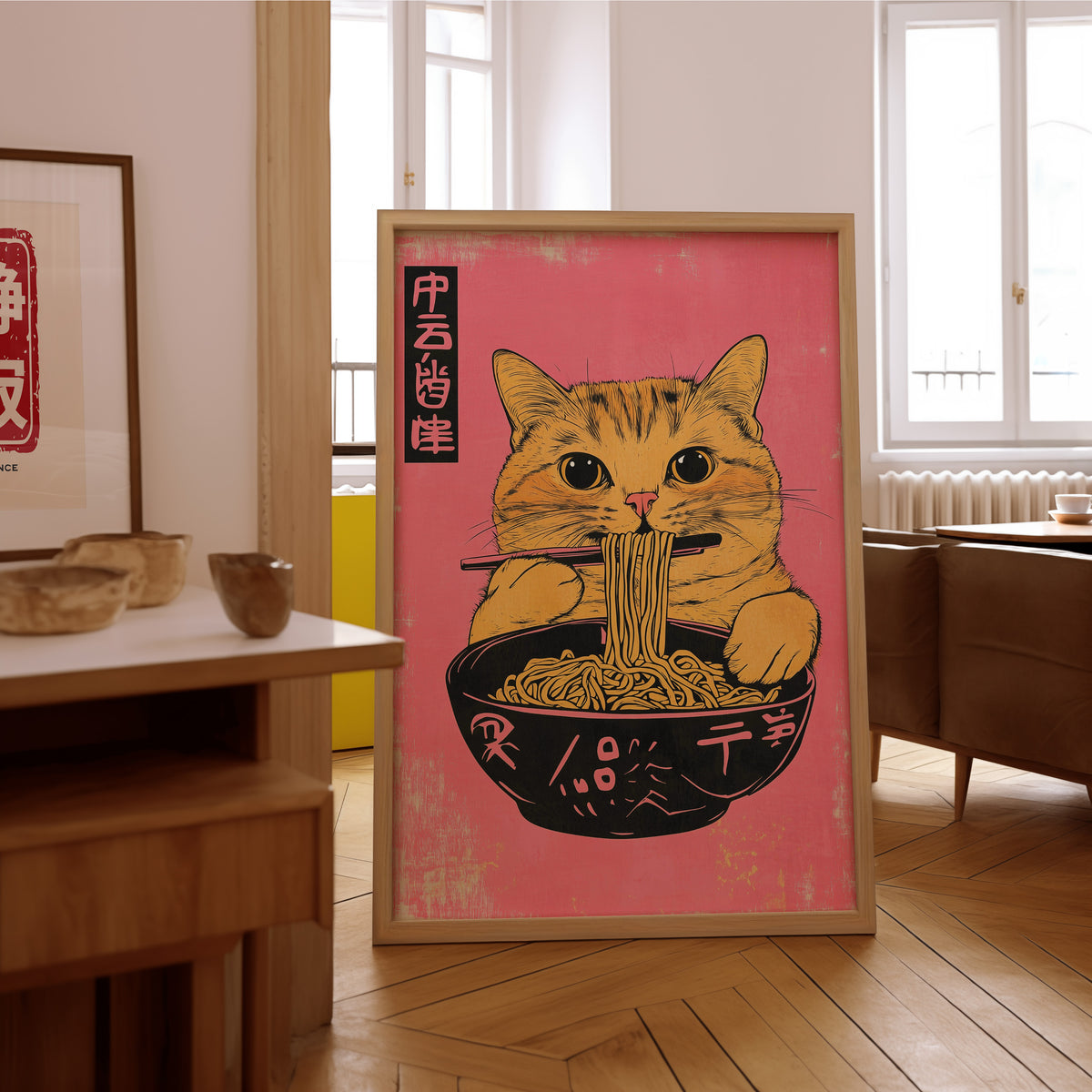 Orange tabby cat slurping ramen print in an oak frame on the parquet floor of a sunlit living room