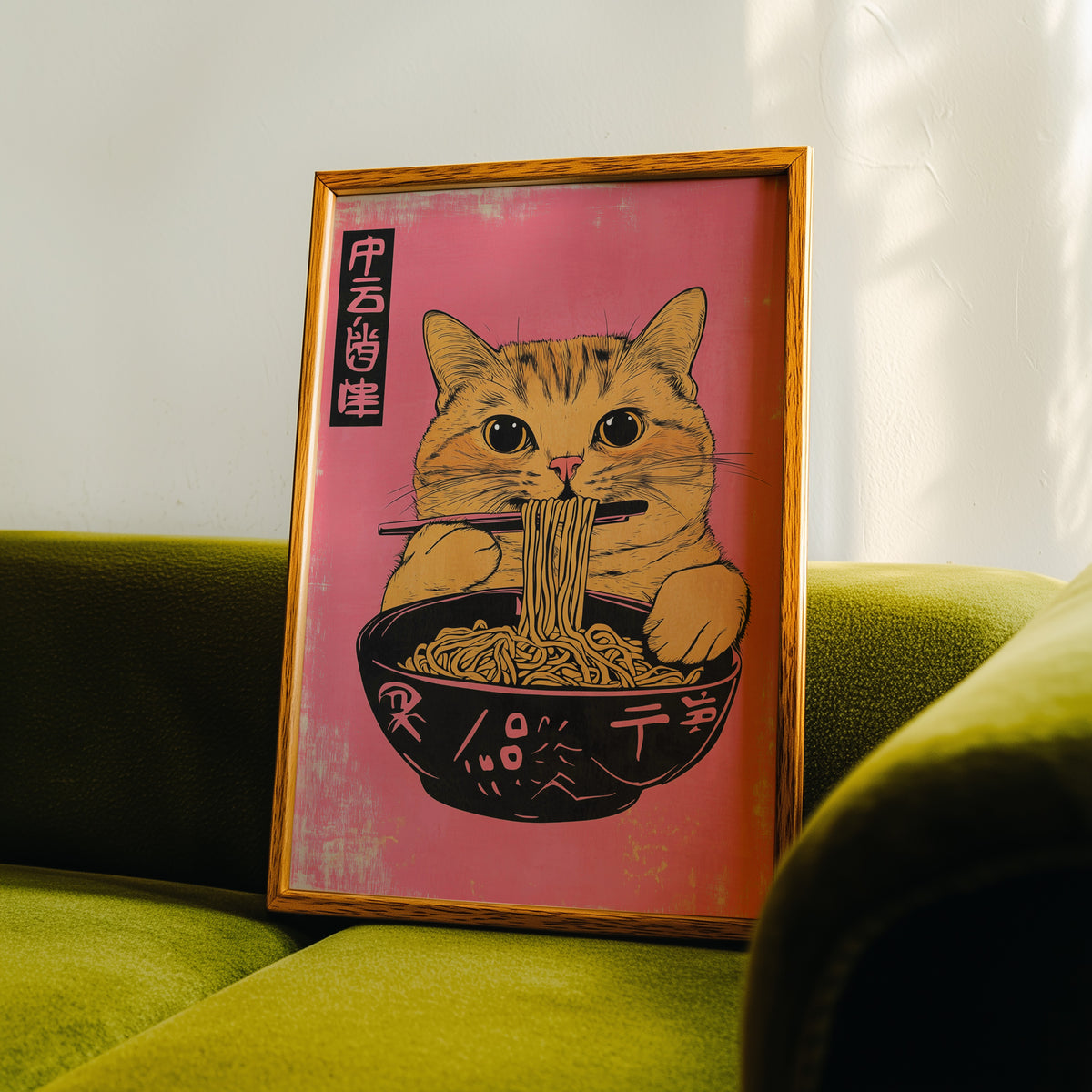 Orange tabby cat slurping ramen print in an oak frame propped on a green velvet sofa